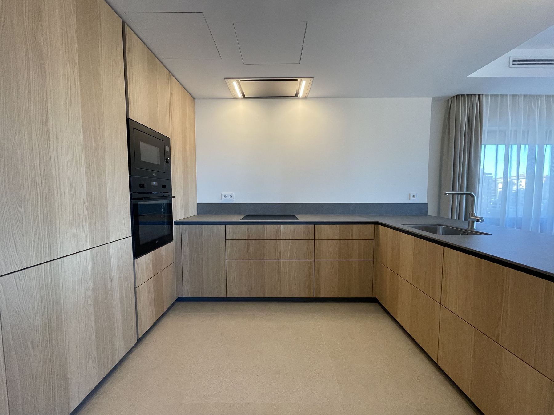 Cocina en roble con columnas de horno y encimera oscura